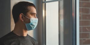 Man in mask looking out of window