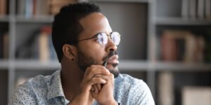 Man with hands at face looking off into the distance